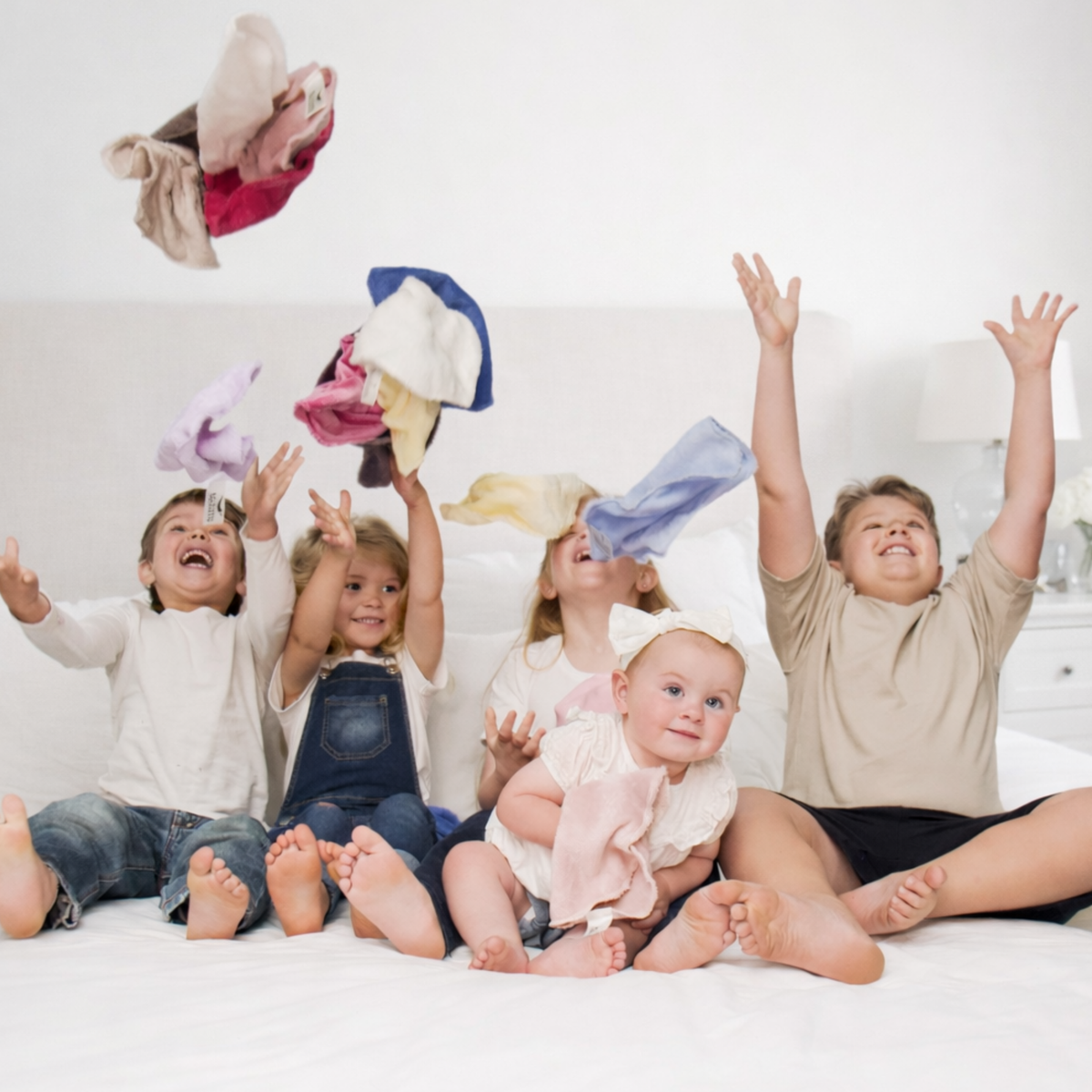 Happy kids and a baby tossing colourful KC Cloths face cloths in the air